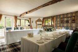 Elegant dining room setup with white tablecloths, floral centerpieces, and decorative elements in a cozy, light-filled space.