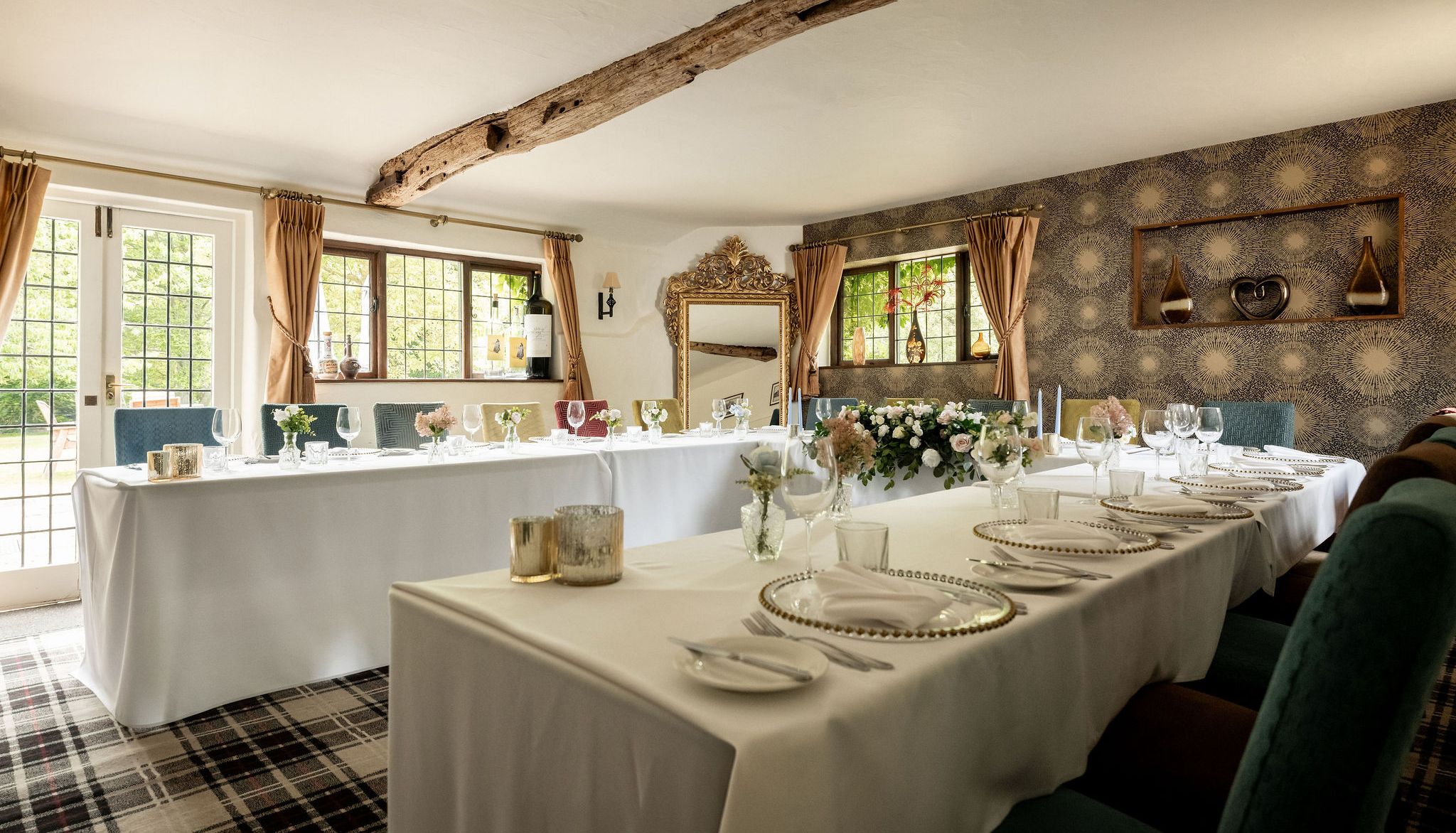 Elegant dining room setup with white tablecloths, floral centerpieces, and decorative elements in a cozy, light-filled space.