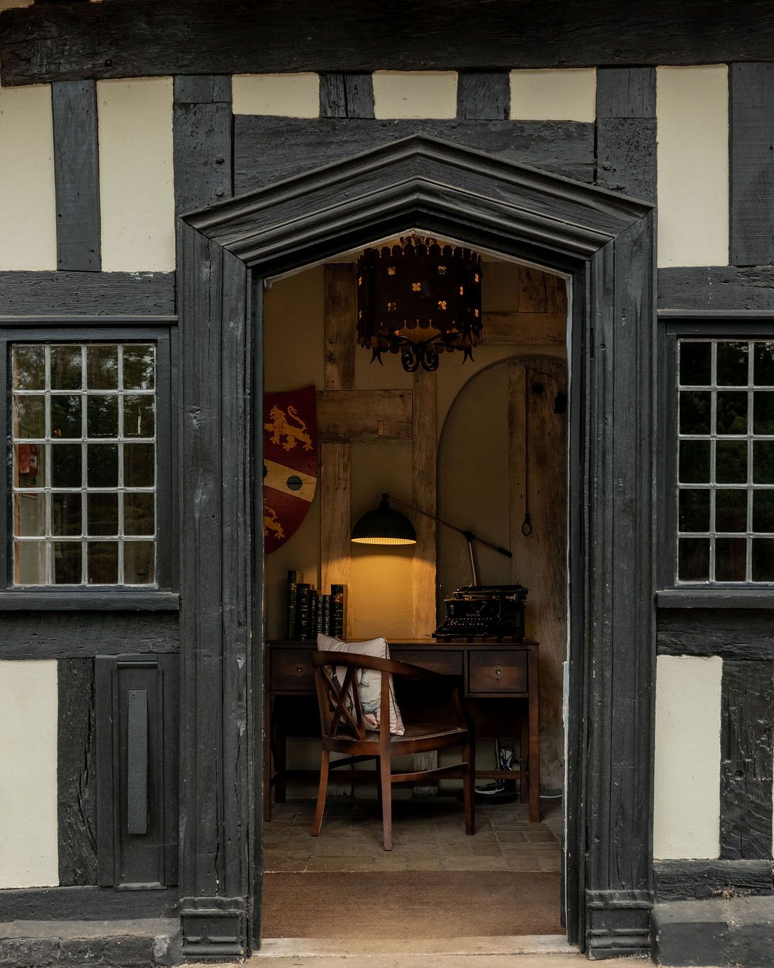 Entrance to a historic timber-framed building with a view of a vintage office desk inside.