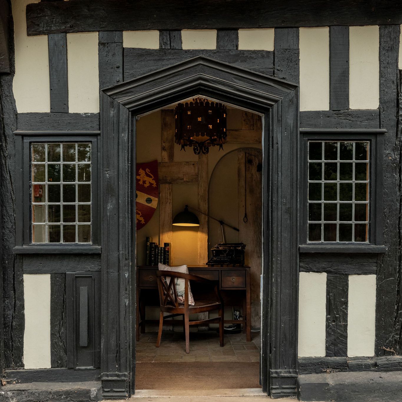 Entrance to a historic timber-framed building with a view of a vintage office desk inside.