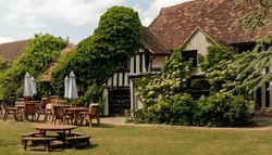 Traditional English countryside building with outdoor seating and lush greenery