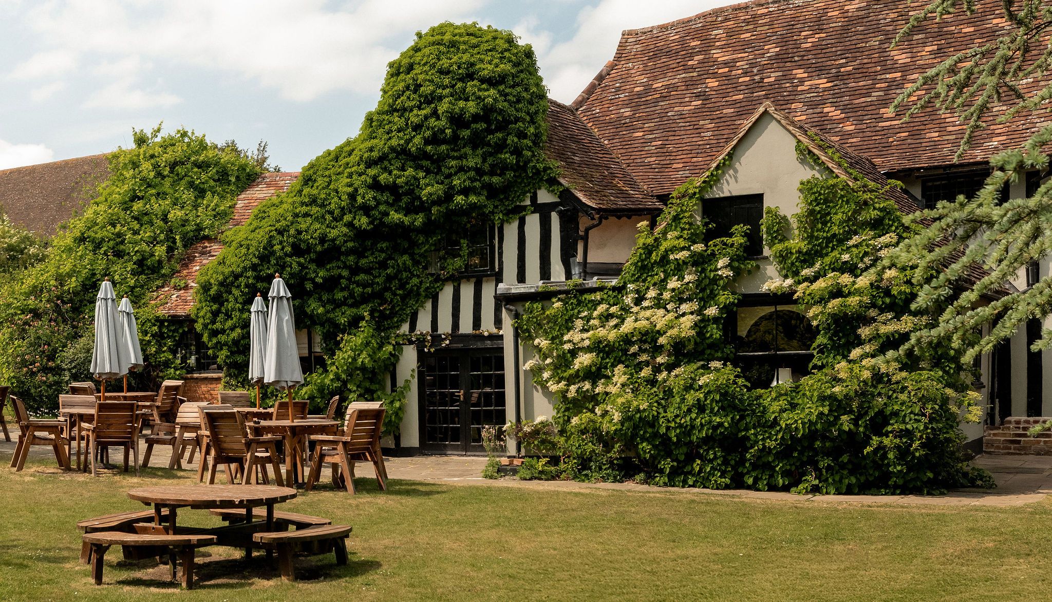 Traditional English countryside building with outdoor seating and lush greenery