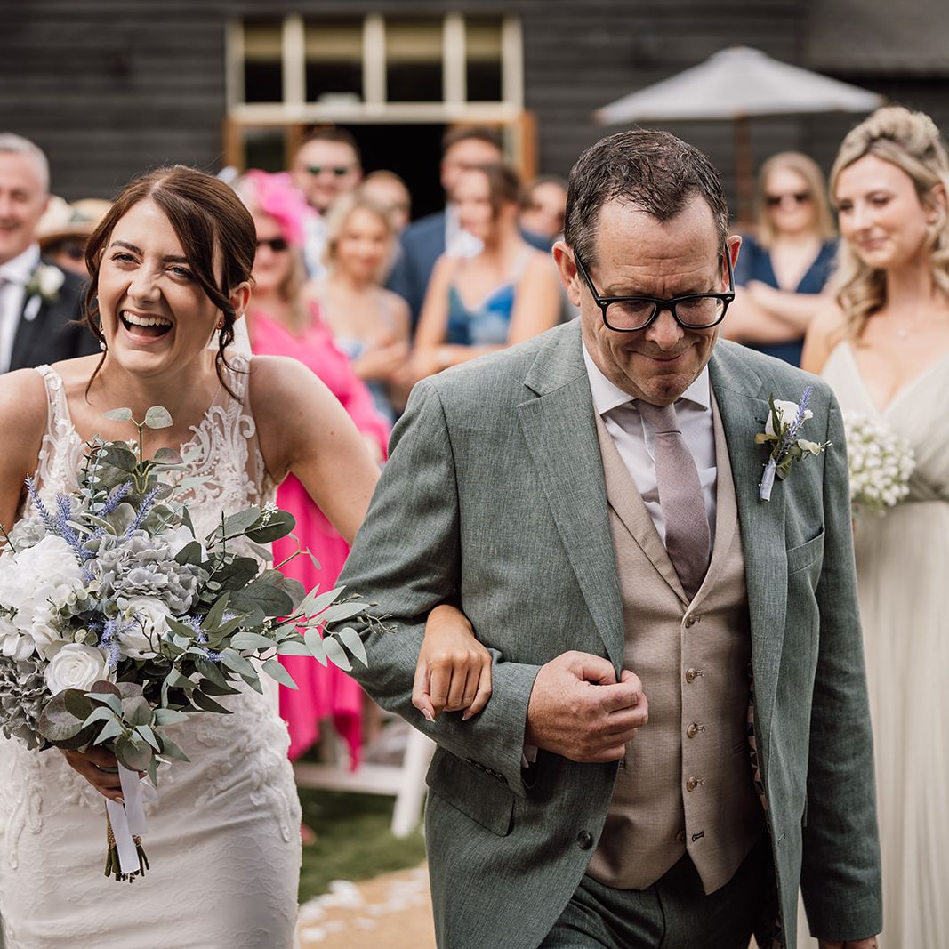 Exterior view of a traditional English countryside pub with wooden tables and benches on a grassy lawn.