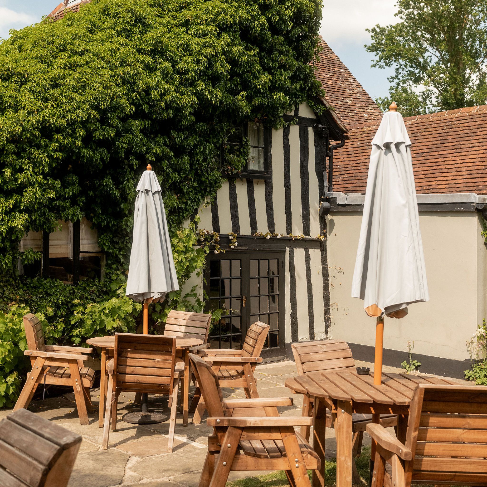 Outdoor seating at a traditional cottage with timber framing and ivy-covered walls.