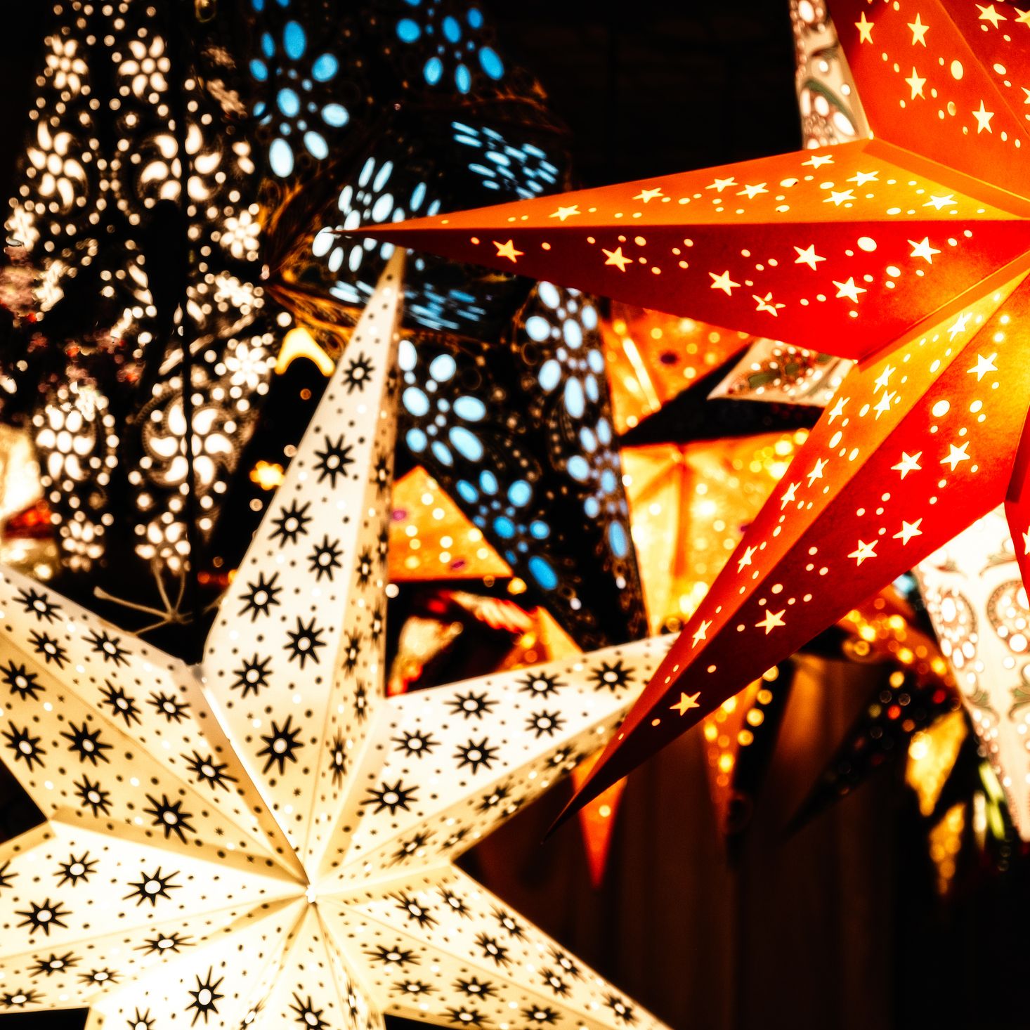 A newlywed couple walks down the aisle outdoors beneath a decorated gazebo, smiling and celebrating as guests applaud on either side.
