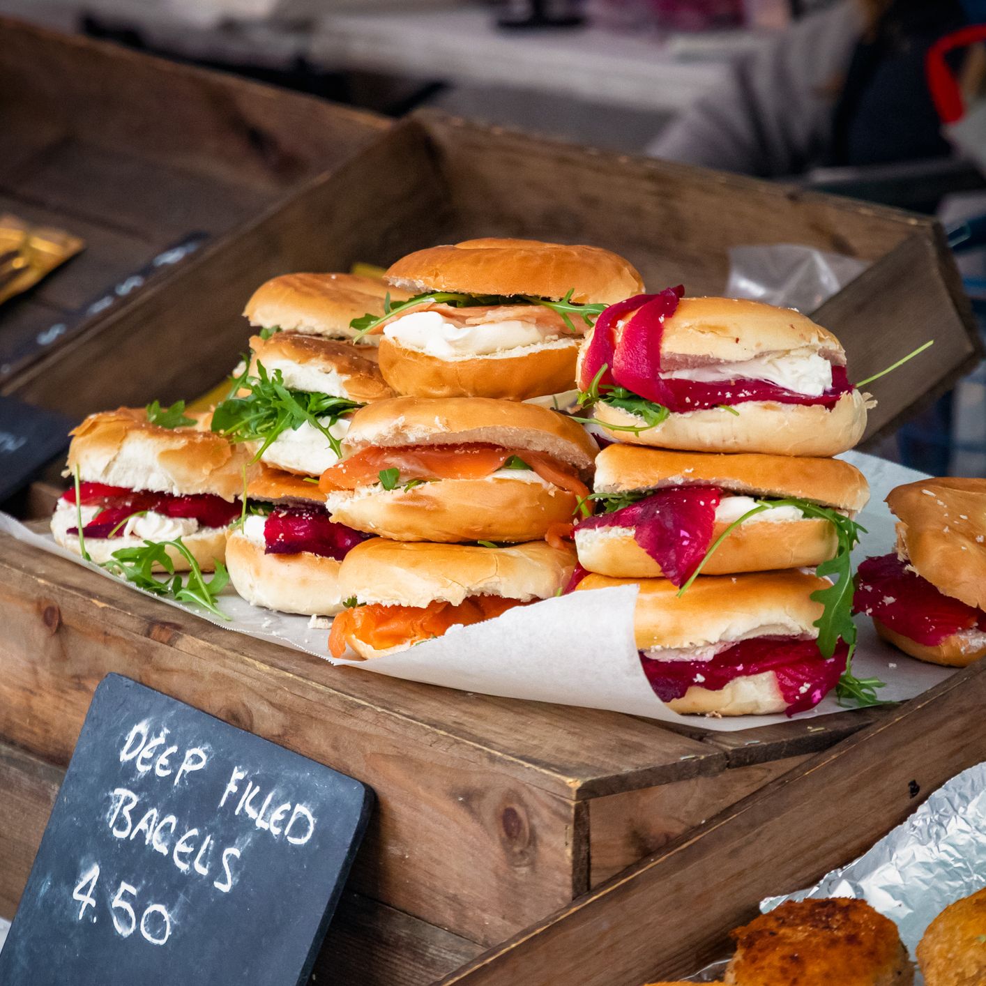 Bride and groom walking hand in hand while guests throw flower petals at their wedding celebration outside a rustic building.