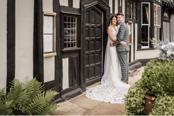 Bride and groom embracing outside a black and white timber-framed building on their wedding day