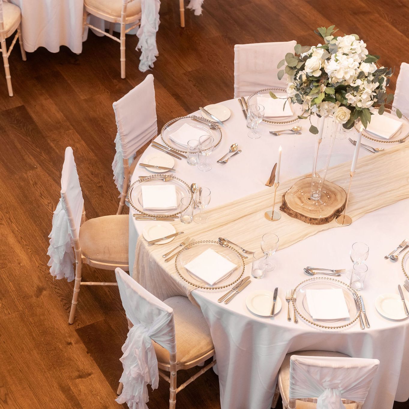 Elegant round table set for a formal event with white tablecloth, decorative centerpiece, and neatly arranged plates and cutlery.