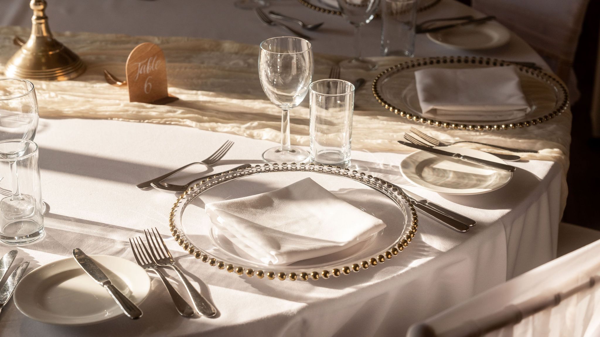 Elegant table setting with gold-rimmed plates, white napkins, and glassware at a formal event.