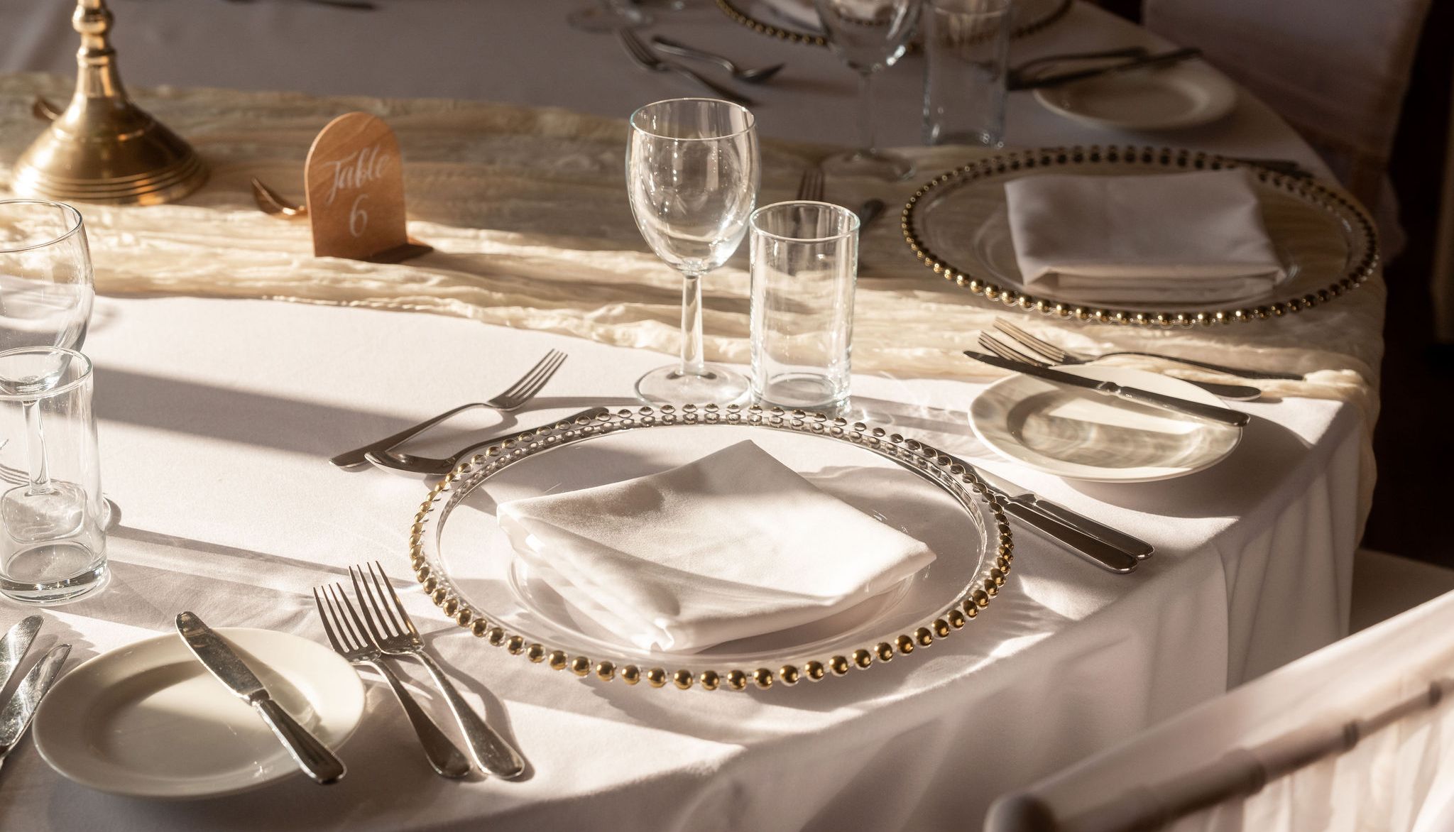 Elegant table setting with gold-rimmed plates, white napkins, and glassware at a formal event.