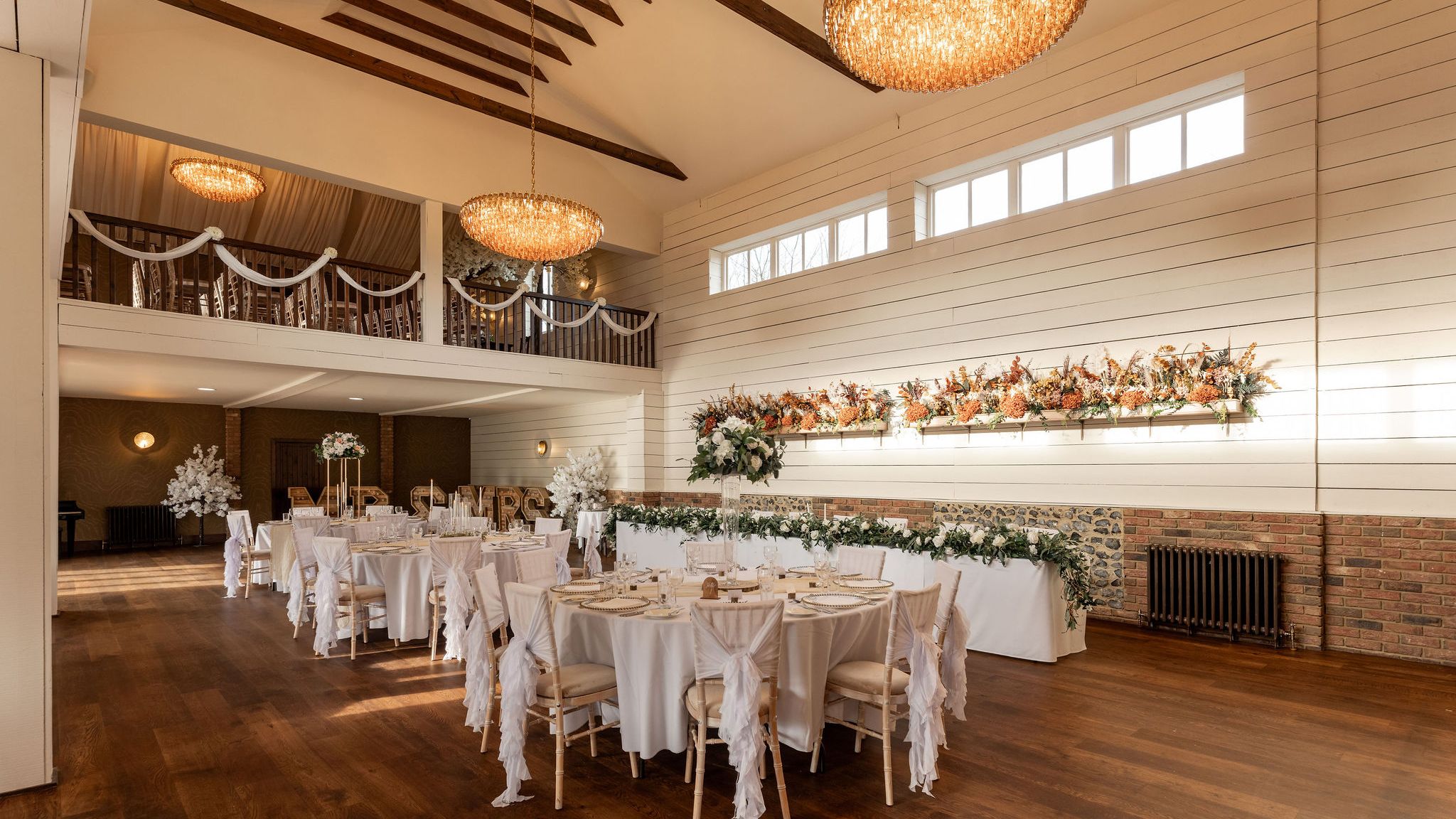Elegant wedding reception hall with white decor, floral arrangements, and chandeliers
