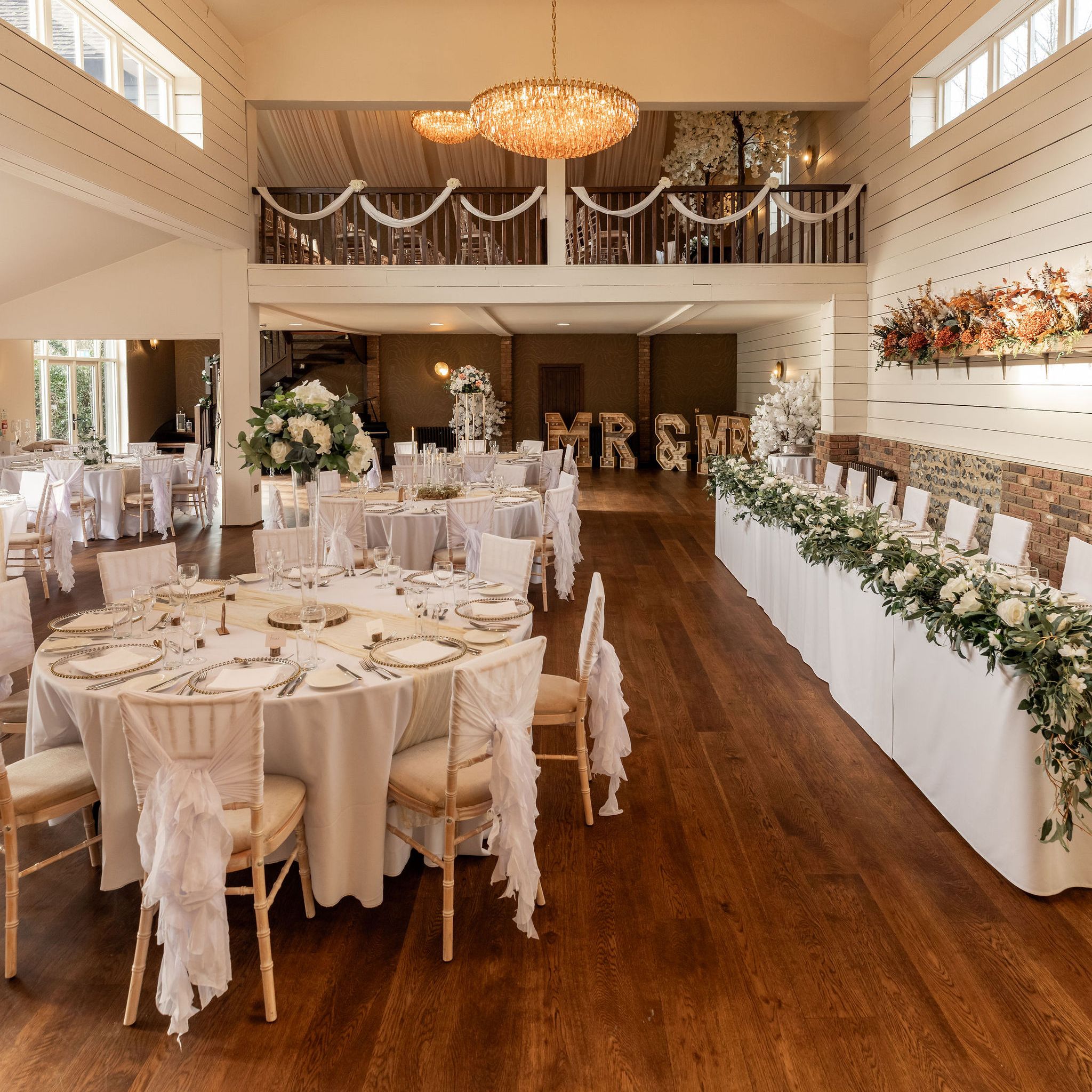 Elegant wedding reception hall with round tables, floral decorations, and chandeliers
