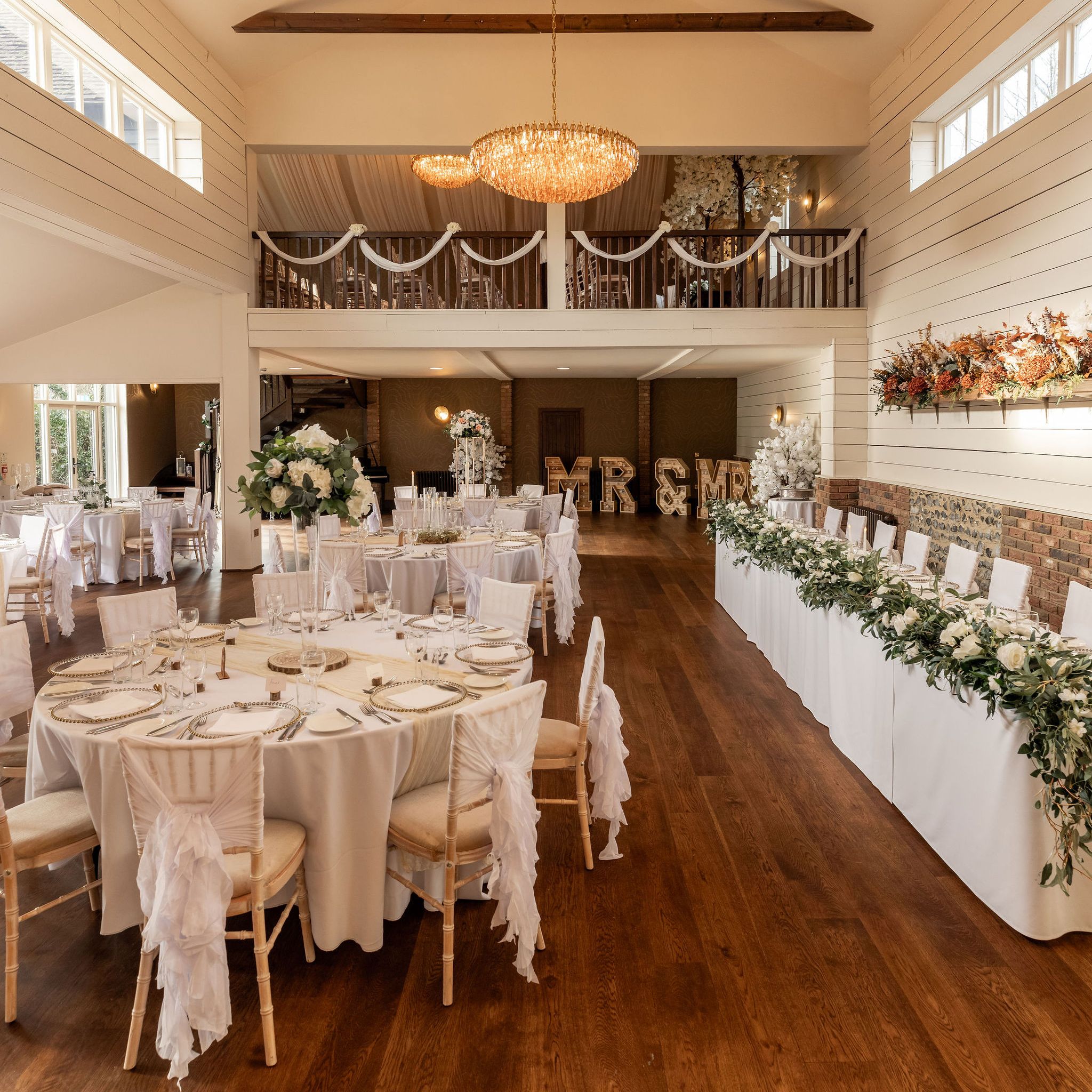 Elegant wedding reception hall with round tables, floral decorations, and chandeliers