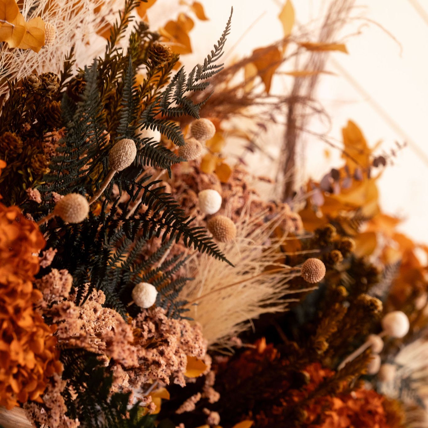 Close-up of a dried autumn floral arrangement with orange and brown tones.