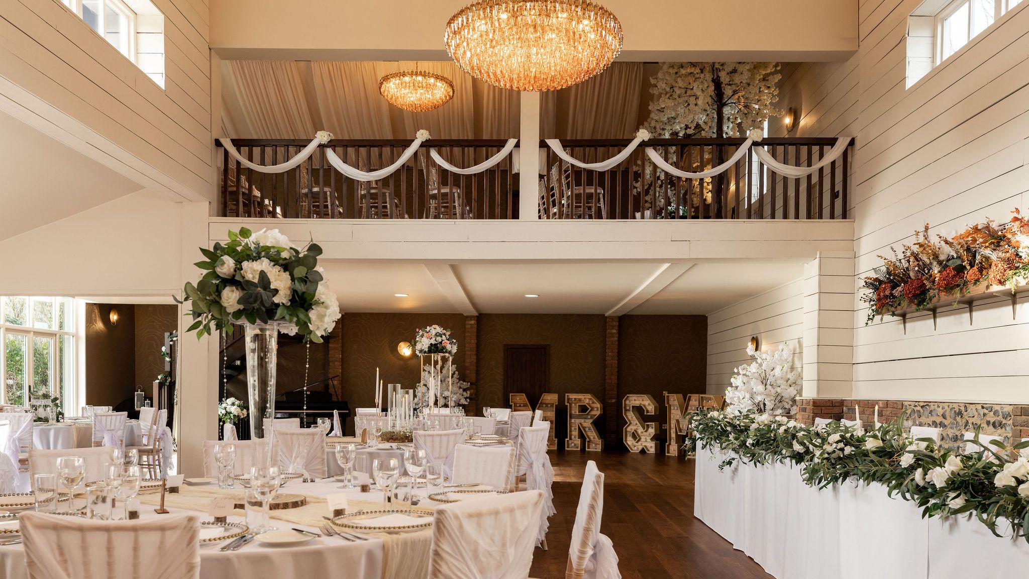 Elegant wedding dining hall with decorated tables, flowers, and large chandelier