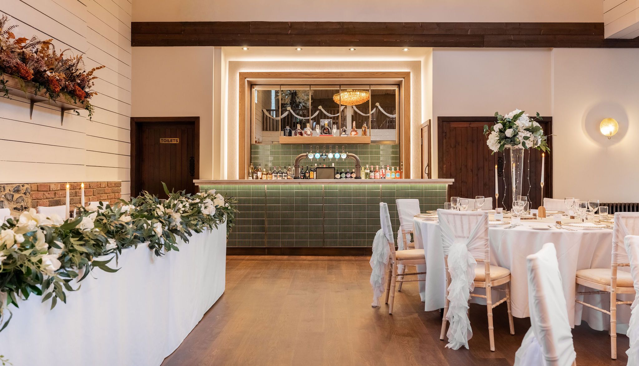 Elegant wedding reception room with a bar, floral arrangements, and decorated tables