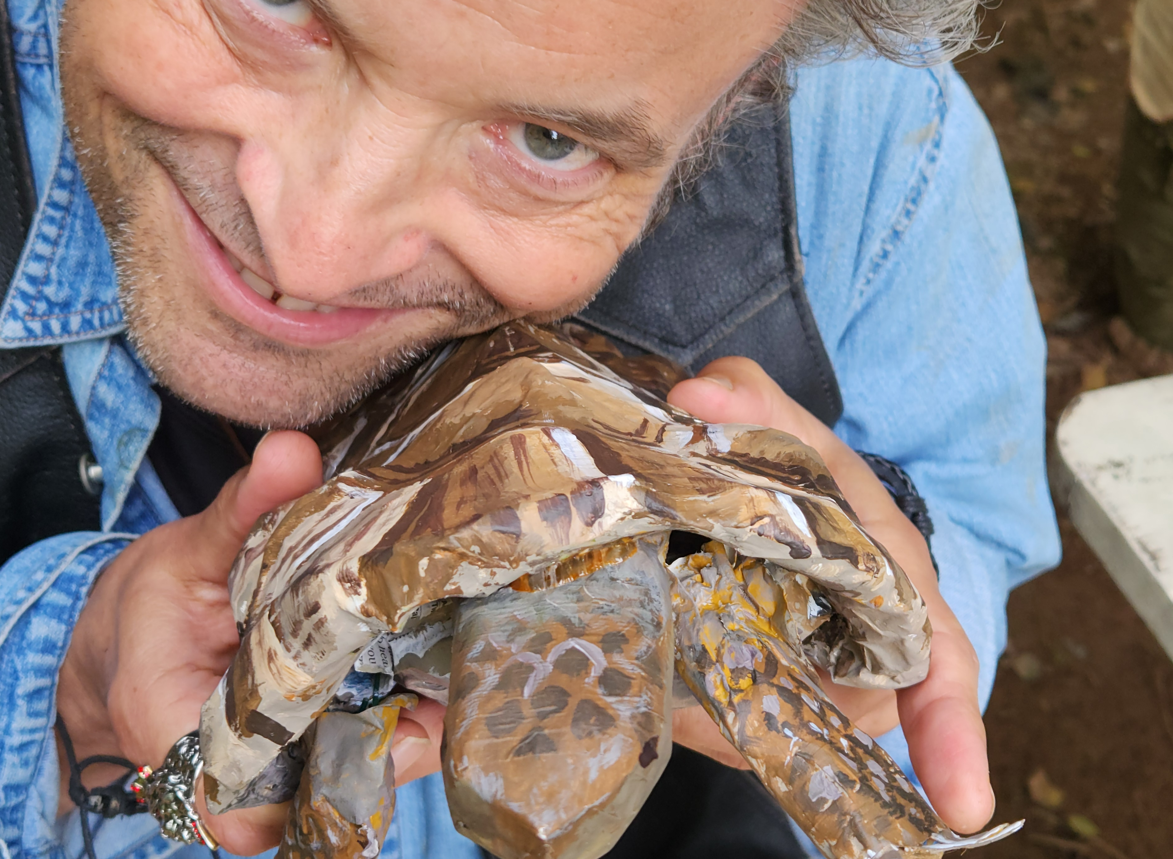Man smiling and holding a realistic looking paper mache turtle