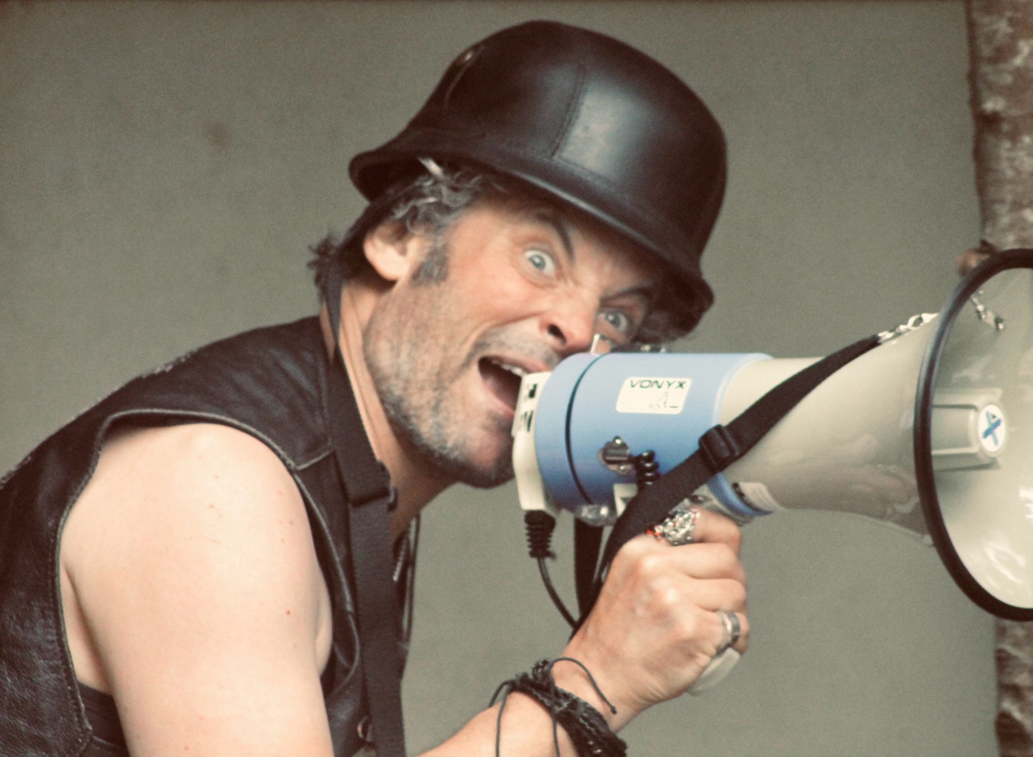 Man with a black helmet shouting into a megaphone