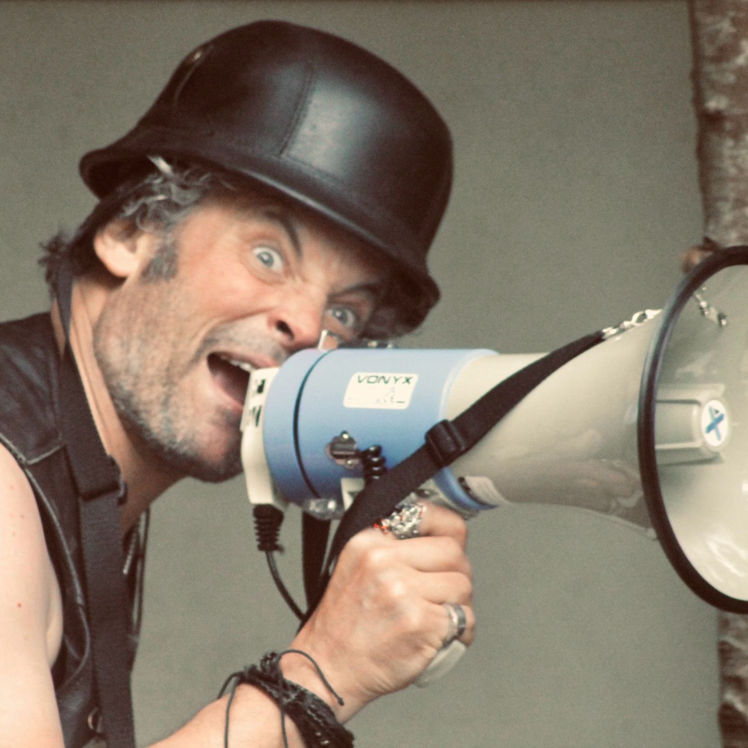 Man with a black helmet shouting into a megaphone