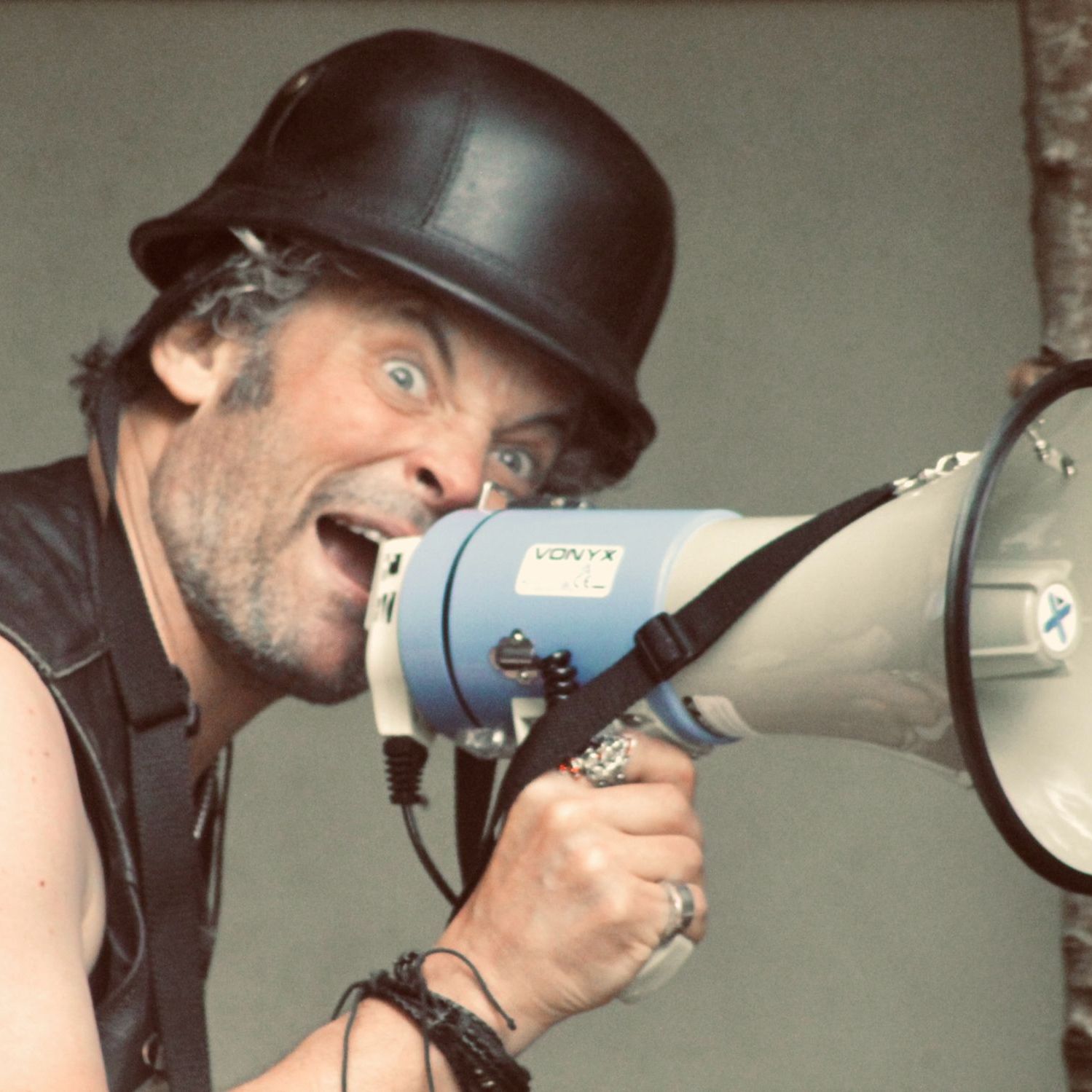 Man with a black helmet shouting into a megaphone