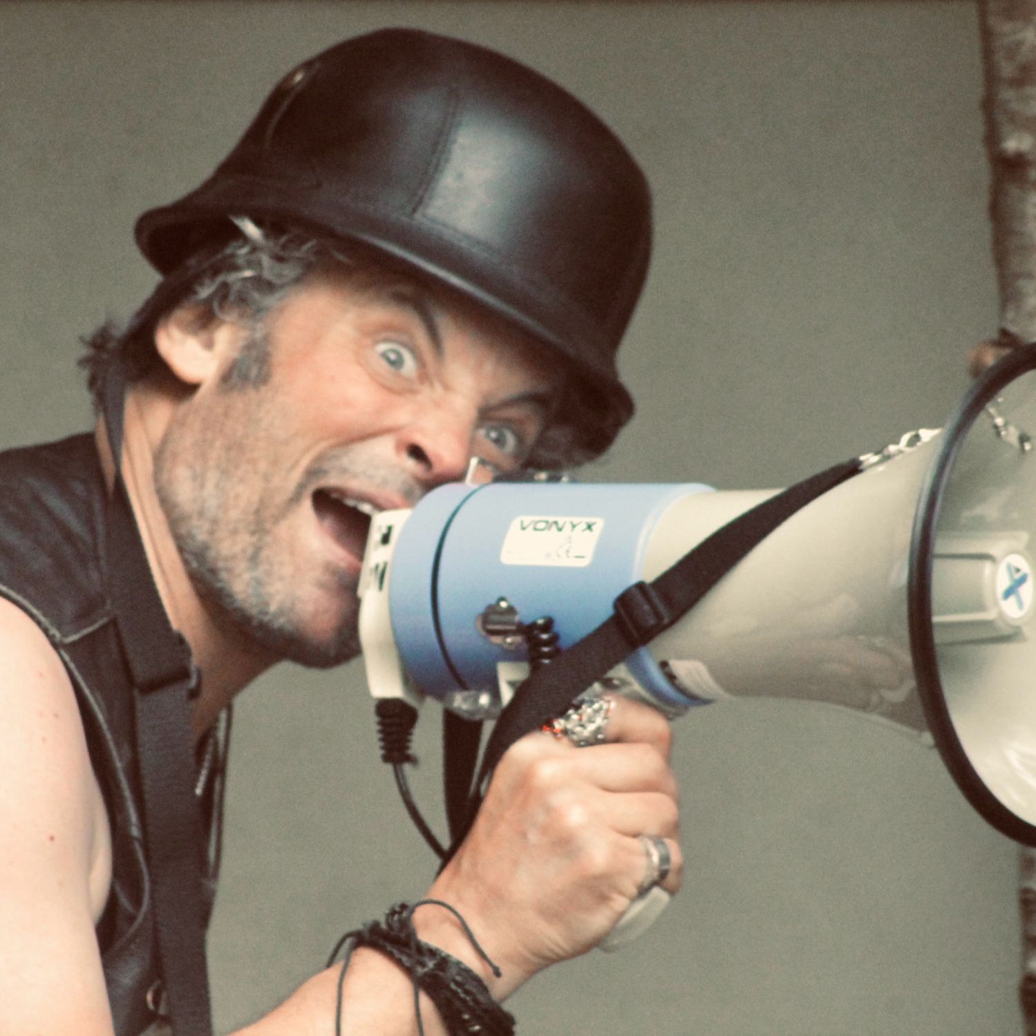 Man with a black helmet shouting into a megaphone
