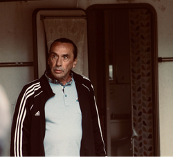 Man standing in front of an open door wearing a black Adidas jacket