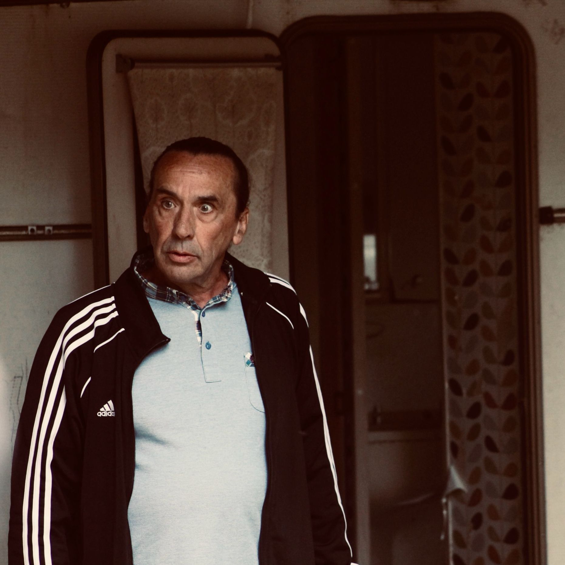 Man standing in front of an open door wearing a black Adidas jacket