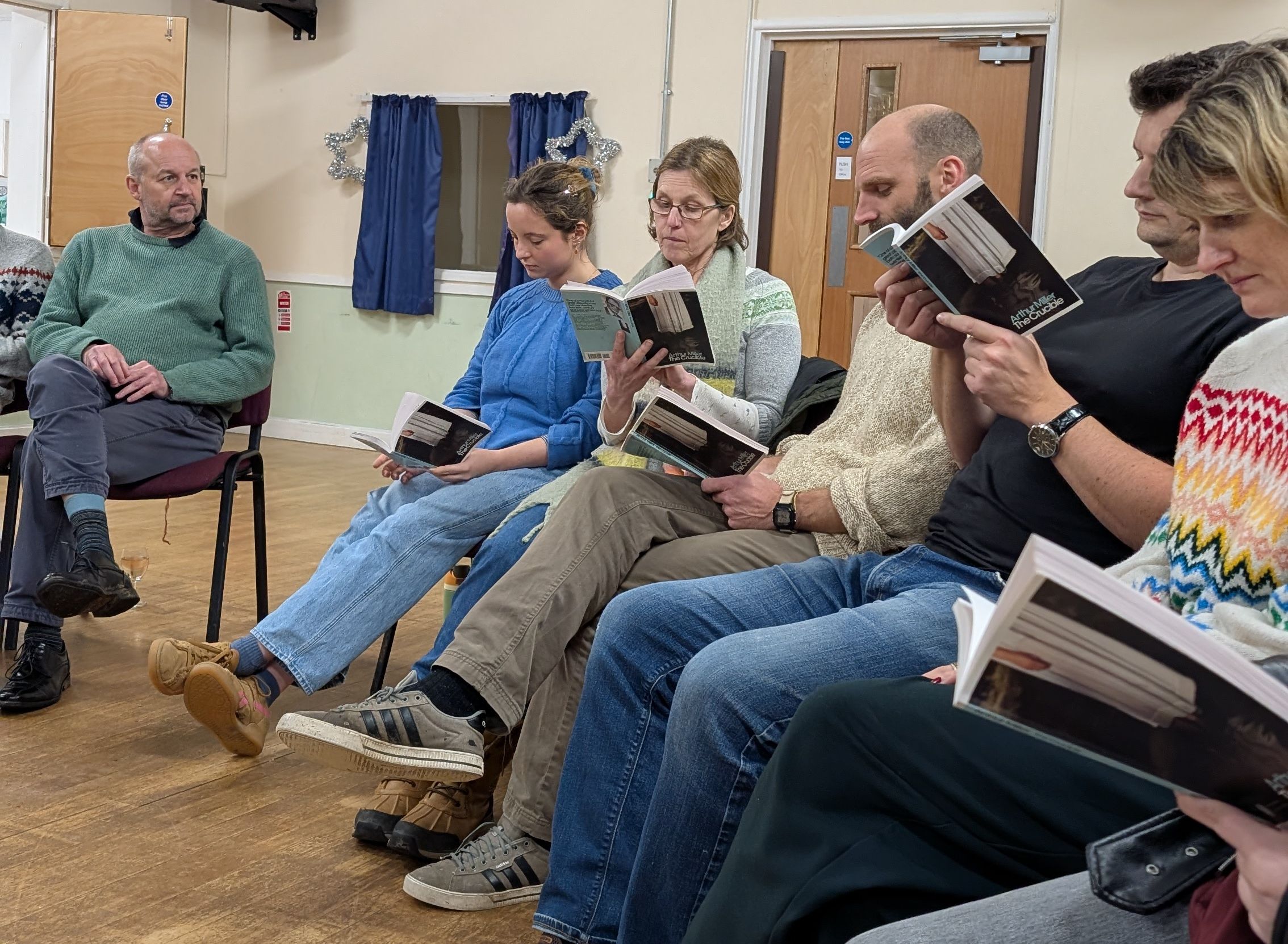 A group of people sitting in a circle reading books in a decorated room.