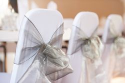 Sliver bows tied around white chairs