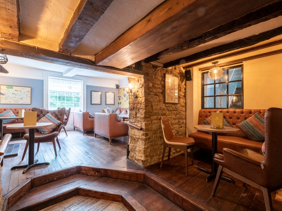 Cozy pub interior with rustic wooden beams, stone walls, and comfortable seating areas