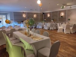 Elegant banquet hall with decorated tables, white chair covers, and colorful balloons