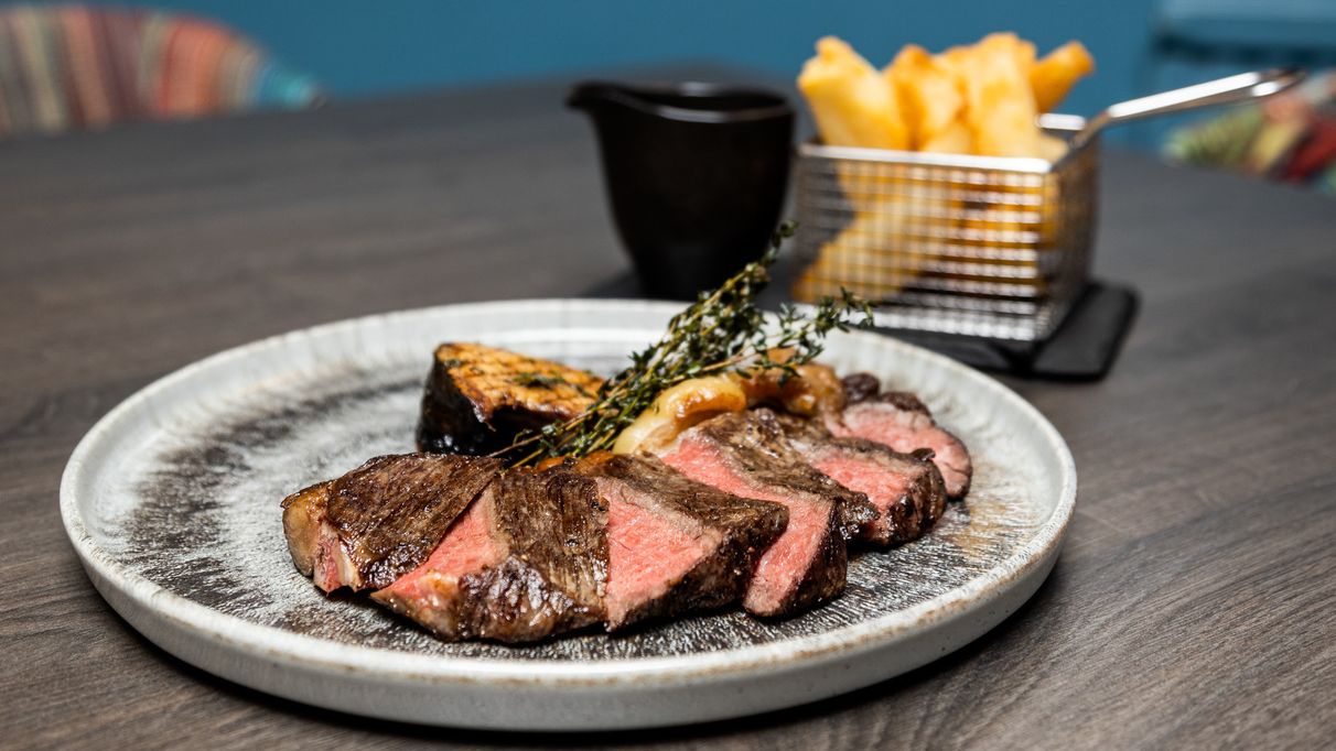 Side view of steak dish with a side of fries