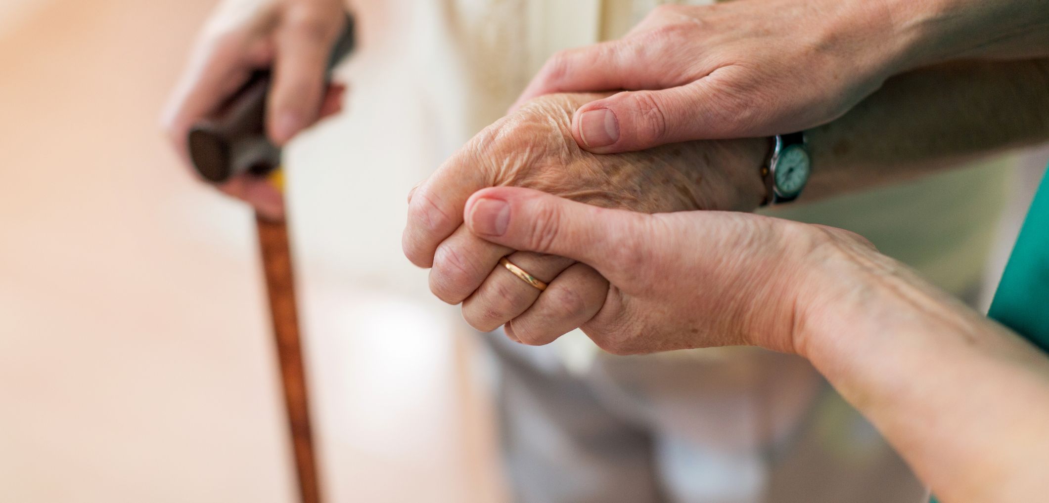 Close-up of a caregiver gently holding the hand of an elderly person using a cane, illustrating compassion in supporting various types of dementia.