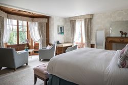 Large open bedroom with arm chairs in the windows