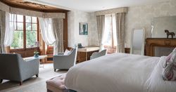 Large open bedroom with arm chairs in the windows