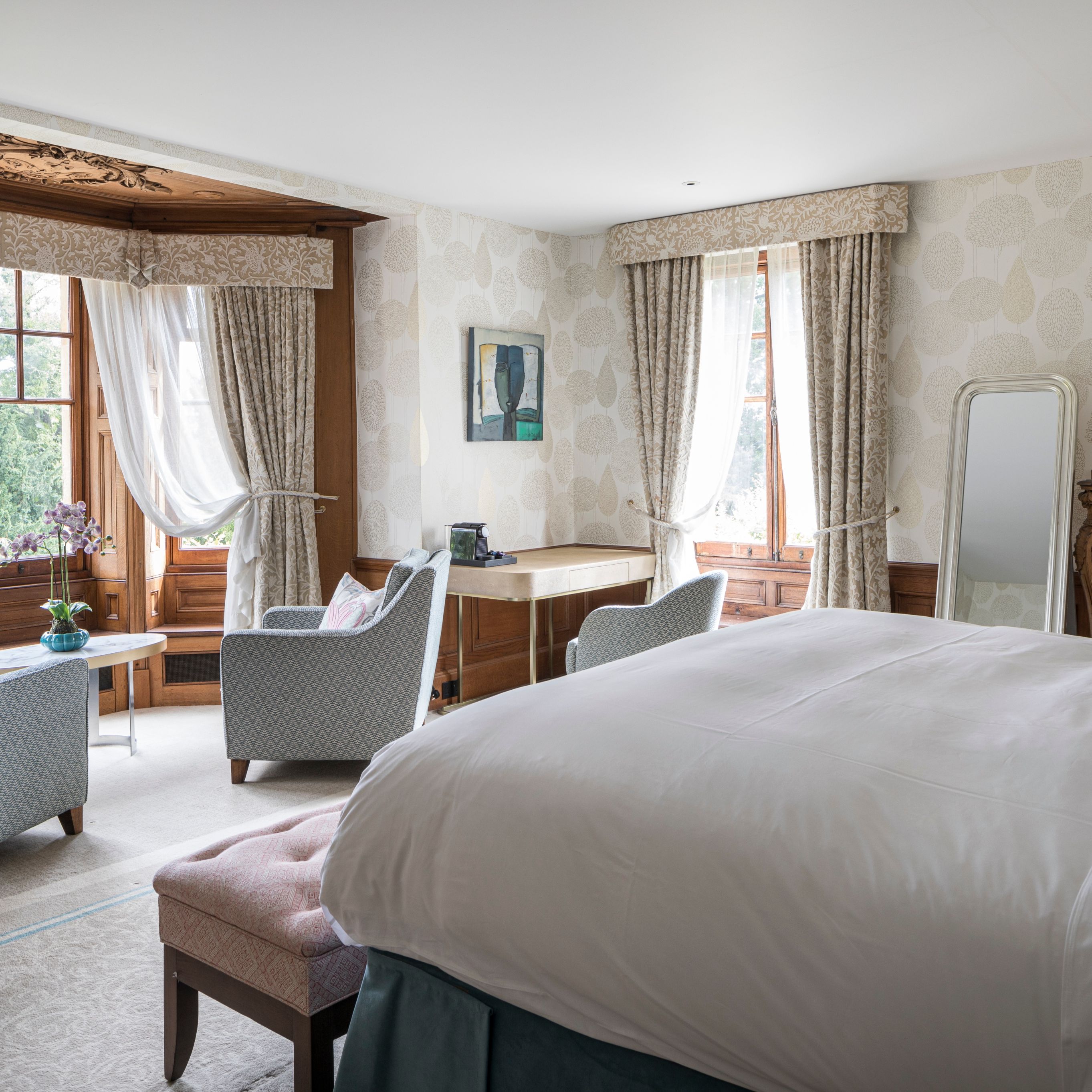 Large open bedroom with arm chairs in the windows