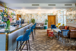 View of the bar with blue velvet chairs, and a sofa in the corner