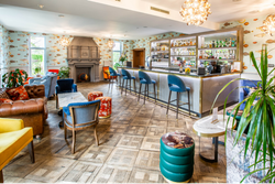 A view of the bar area and surroundings, lots of multicoloured chairs around a codffee table