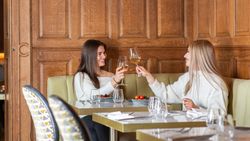 Two Ladies Holding Wine Glass sat on a row of tables