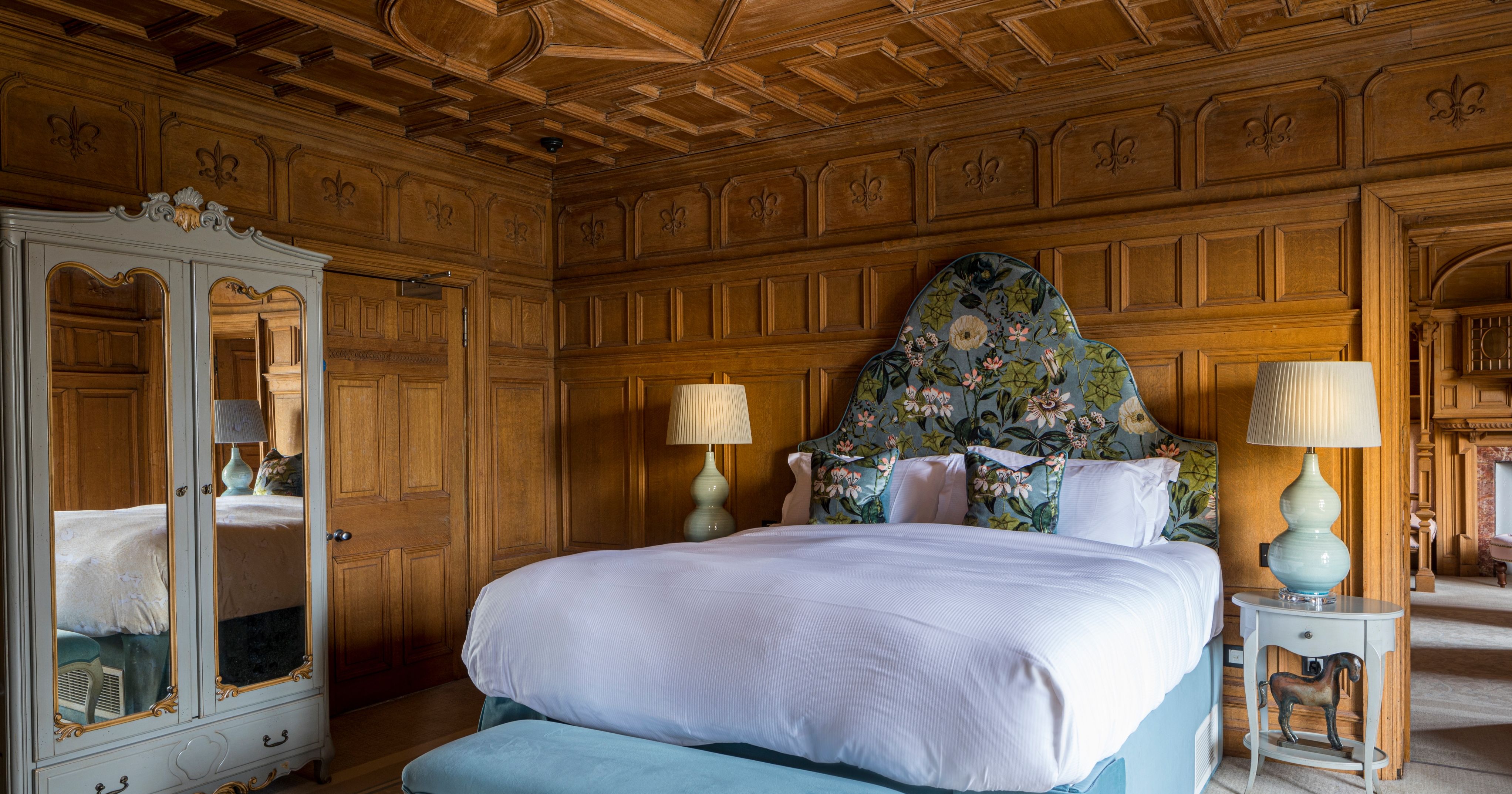 Large wood panelled bedroom with feature headboard and plush furniture