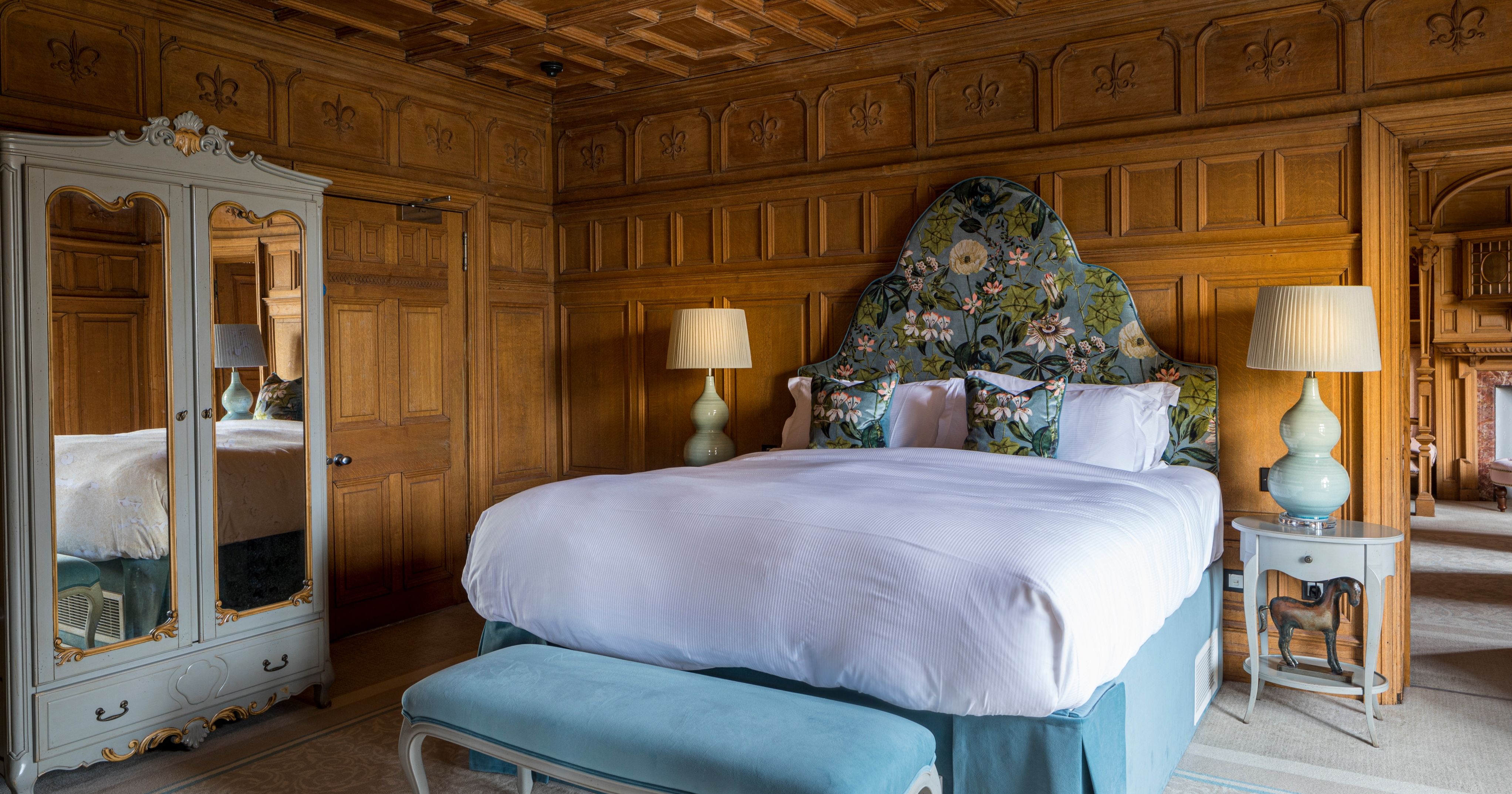 Large wood panelled bedroom with feature headboard and plush furniture