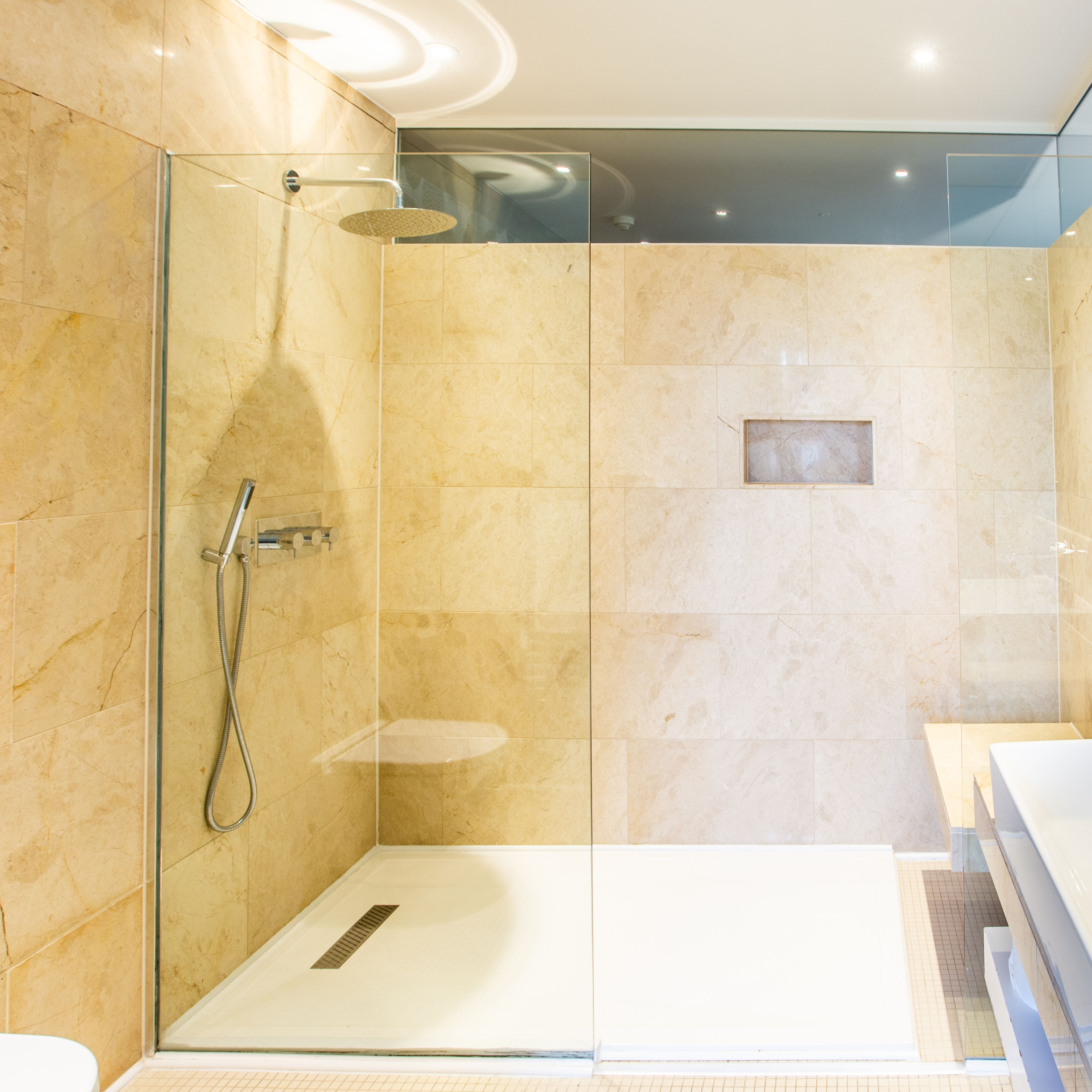 Bathroom with Spacious Shower and sink with brown tiled walls