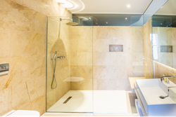 Bathroom with Spacious Shower and sink with brown tiled walls
