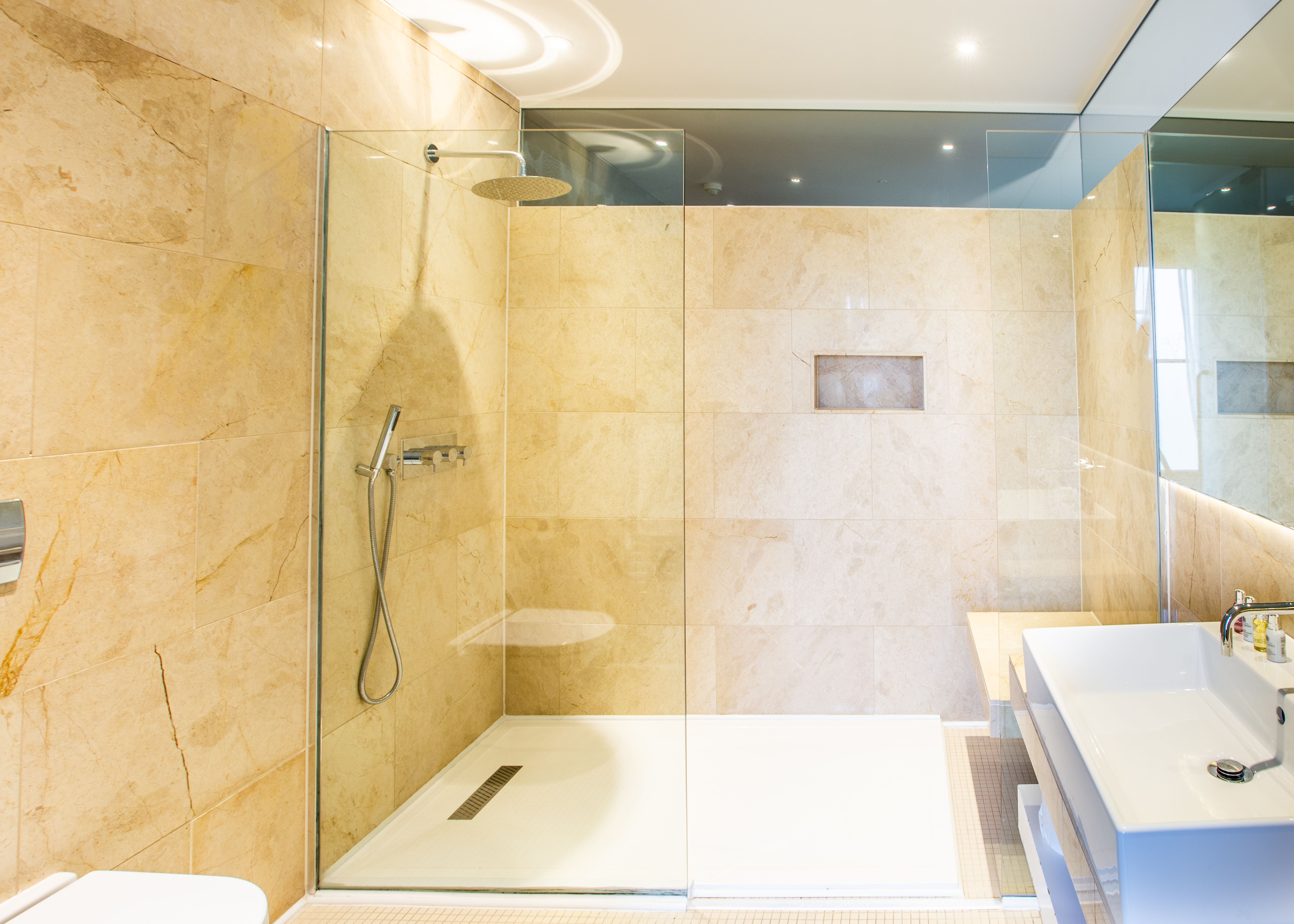 Bathroom with Spacious Shower and sink with brown tiled walls