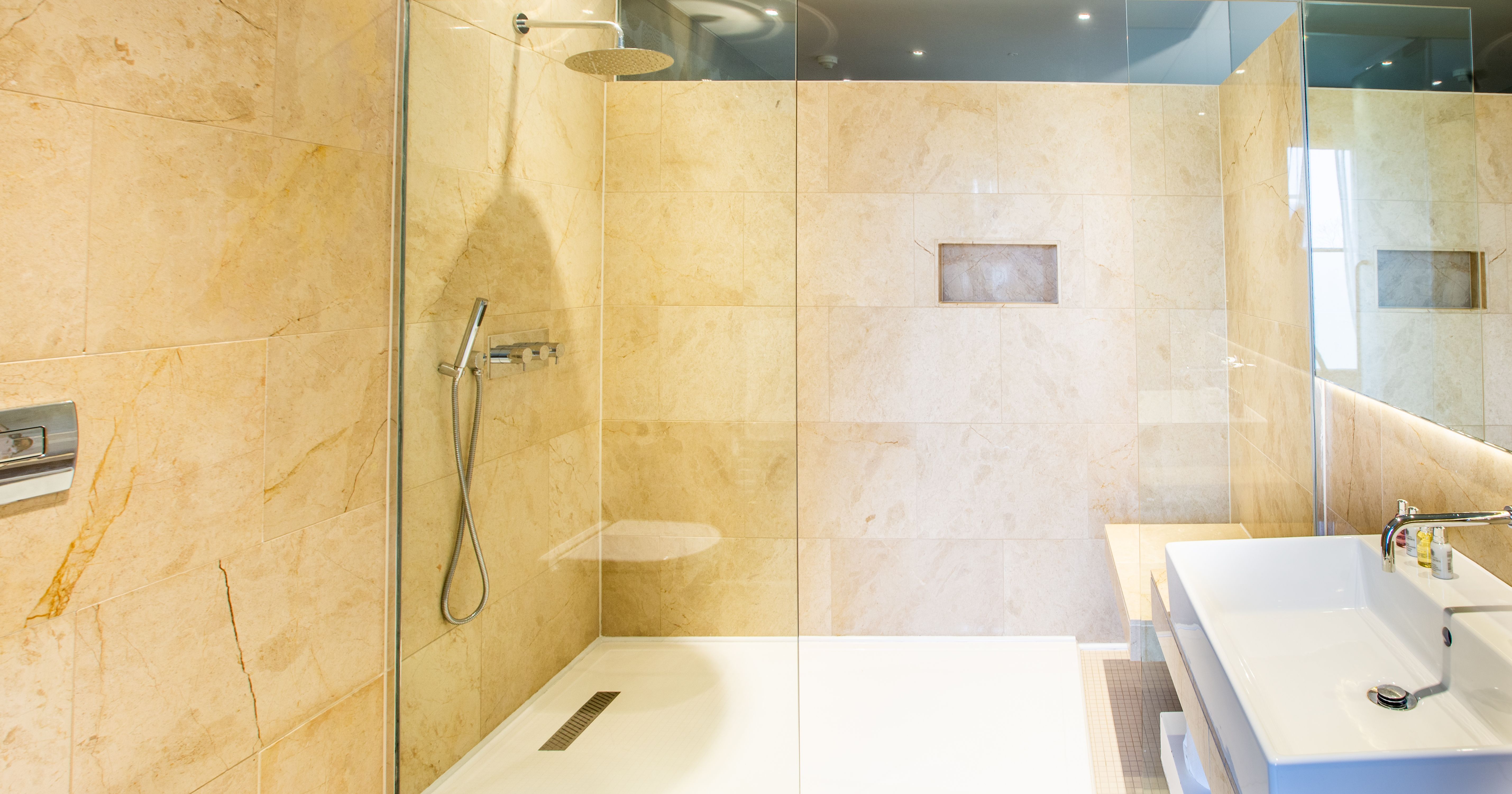 Bathroom with Spacious Shower and sink with brown tiled walls