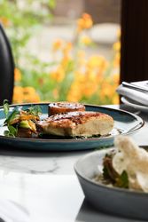 Meal on a plate with large windows with orange flowers