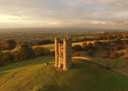 Aerial view of Broadway Tower on a hilltop at sunset with views over the Cotswold countryside