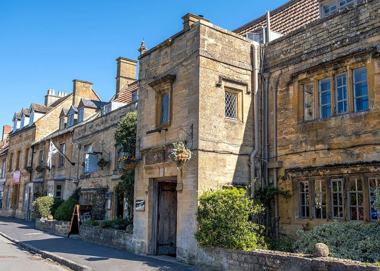 Historic golden stone buildings on a sunny street in Moreton-in-Marsh, Cotswolds