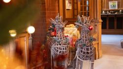 Two decorative wicker reindeer in a festive holiday setting with presents and garland in a warmly lit room.