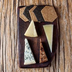Assorted cheeses and crackers on a dark wooden serving board